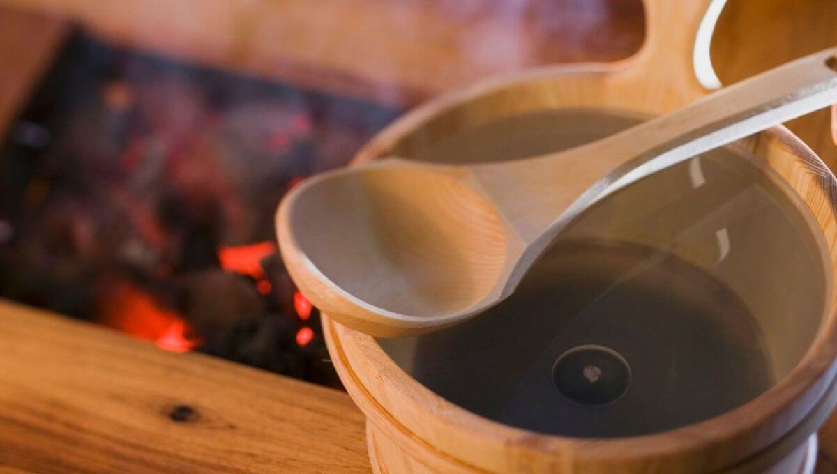 Dùng xô gáo gỗ để tưới nước lên đá sauna Dùng xô gáo gỗ để tưới nước lên đá sauna