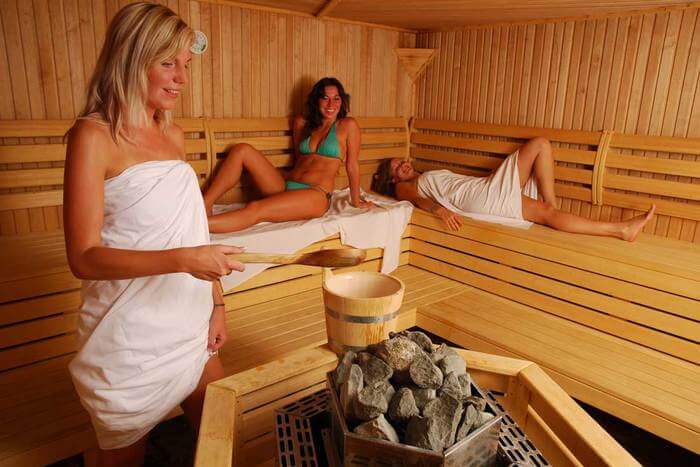 Dùng gáo gỗ rưới nước lên đá sauna tạo nhiệt